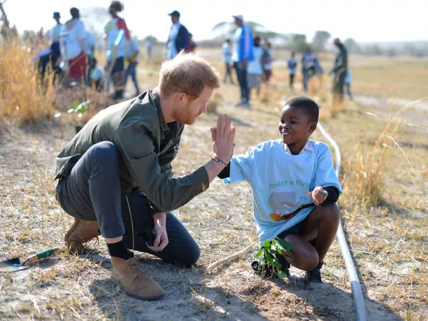 El Príncipe Harry ayuda a los niños de la escuela local a plantar árboles en la Reserva de Árboles Chobe en Botswana el 26 de septiembre de 2019