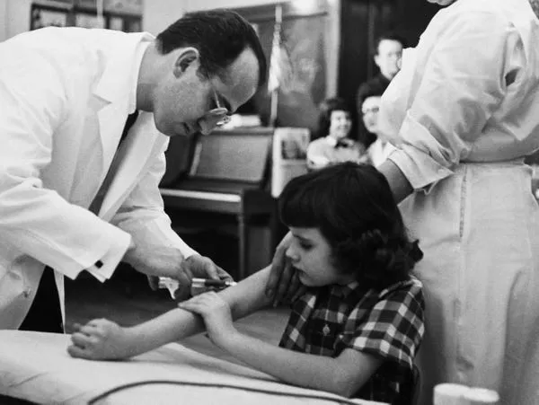 Salk le da una inyección de vacuna a una niña durante ensayos en 1954. Bettmann/Getty Images