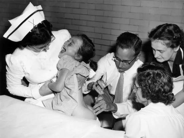 Jonas Salk le da una vacuna a un niño en la década de 1950. Mondadori via Getty Images